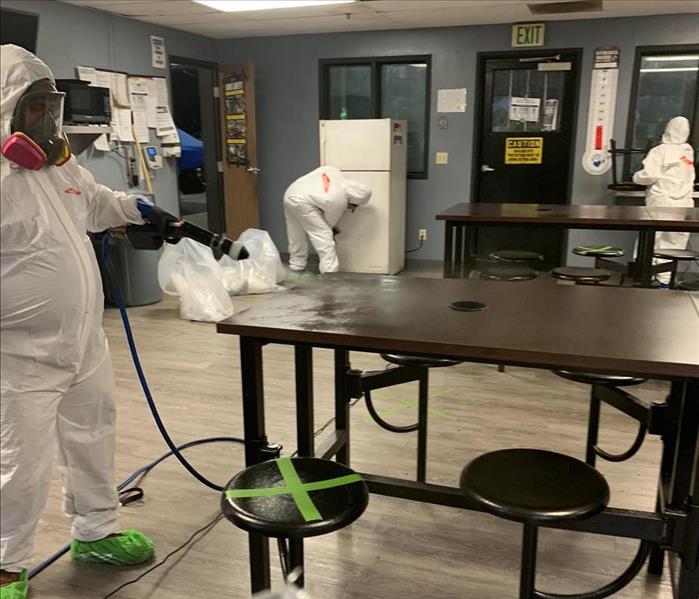 Employees disinfecting area affected by biohazard. 