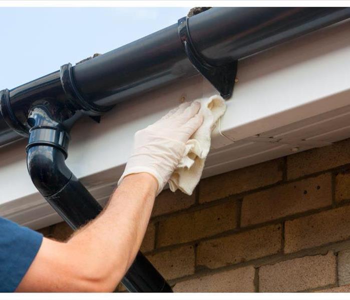 Man cleaning and maintaining plastic guttering