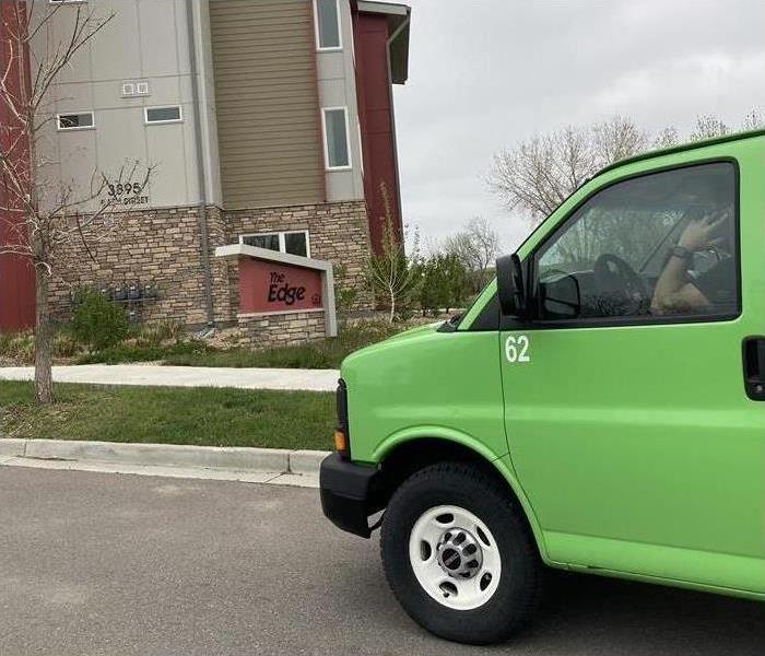 A person inside a green vehicle talking in the phone arriving to a property